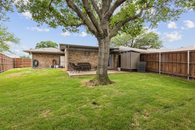 back of house with a yard, a patio, brick siding, and a fenced backyard