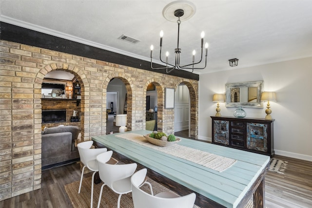 dining room featuring visible vents, wood finished floors, baseboards, arched walkways, and a notable chandelier