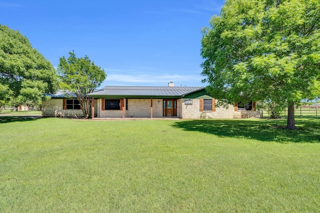 back of property featuring a standing seam roof, a chimney, metal roof, a lawn, and fence