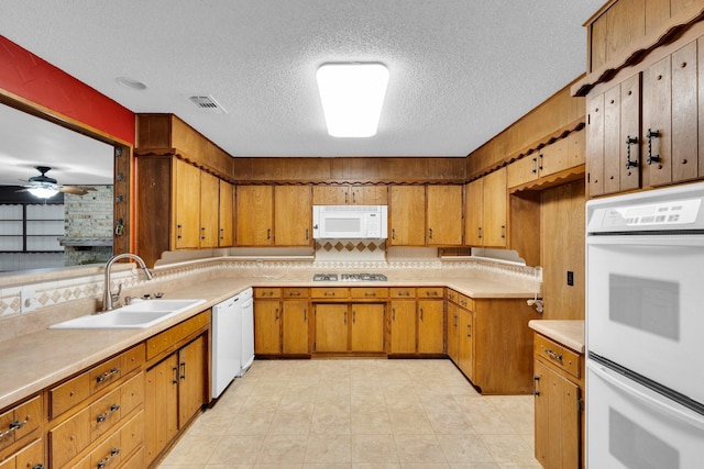 kitchen with ceiling fan, a sink, white appliances, light countertops, and a textured ceiling