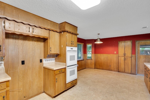 kitchen featuring white double oven, light countertops, a textured ceiling, and visible vents