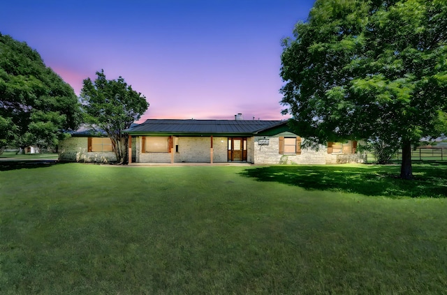 rear view of property with fence, a yard, and brick siding