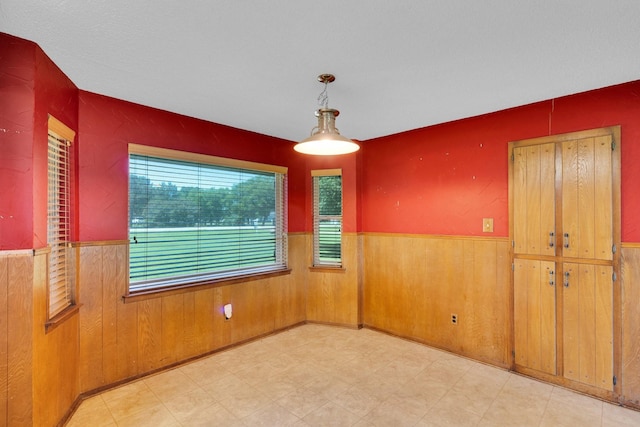 spare room with a wainscoted wall, wood walls, and light floors