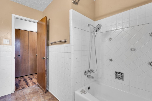 full bathroom featuring wainscoting, shower / bathtub combination, and tile walls