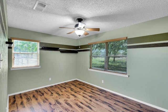unfurnished room featuring ceiling fan, visible vents, plenty of natural light, and wood finished floors