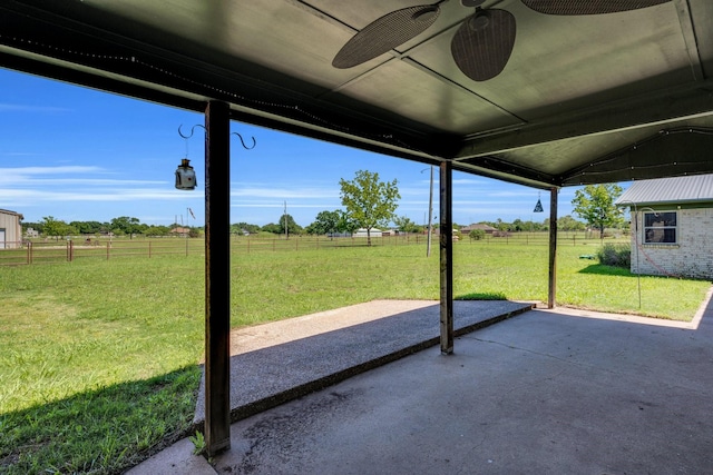 view of patio with fence, ceiling fan, and a rural view