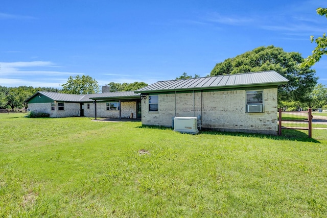 back of property featuring a chimney, a yard, metal roof, and brick siding