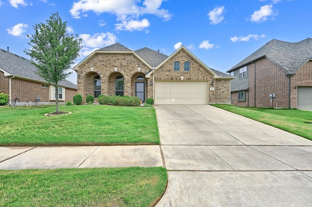 french country style house with an attached garage, concrete driveway, a front lawn, and brick siding