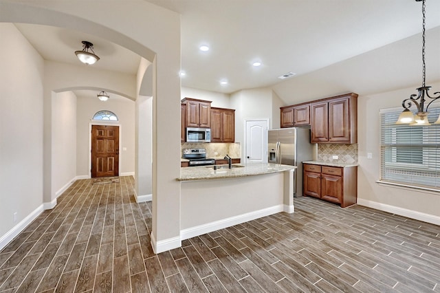 kitchen with dark wood-style flooring, arched walkways, appliances with stainless steel finishes, and tasteful backsplash
