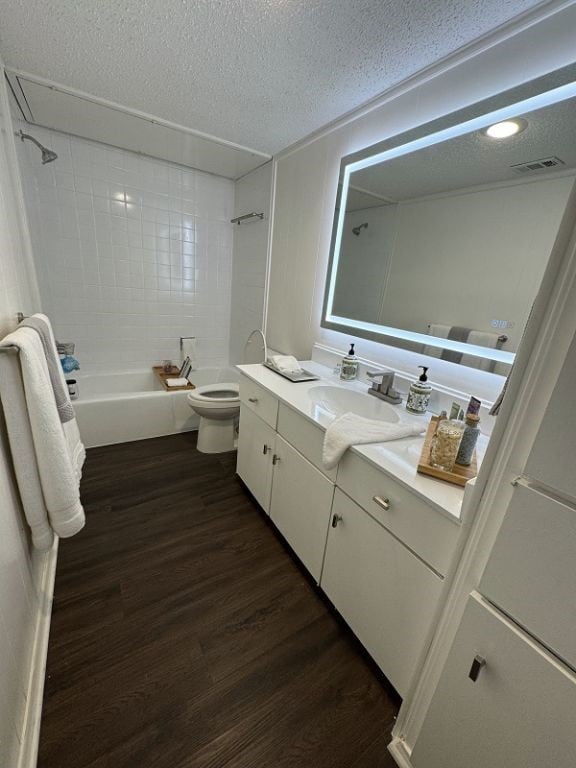full bathroom featuring toilet, a textured ceiling, bathing tub / shower combination, wood finished floors, and visible vents