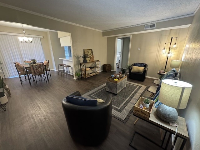 living room featuring crown molding, a notable chandelier, a textured ceiling, wood finished floors, and visible vents