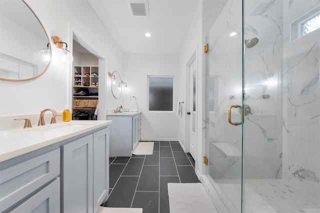 full bath with visible vents, two vanities, a spacious closet, a sink, and a marble finish shower