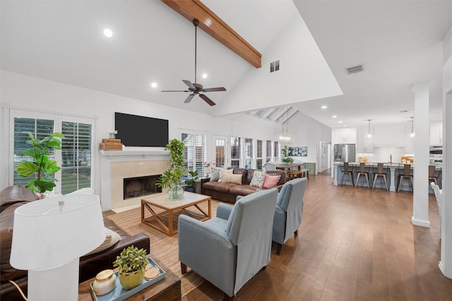 living area featuring a healthy amount of sunlight, a premium fireplace, beam ceiling, and visible vents