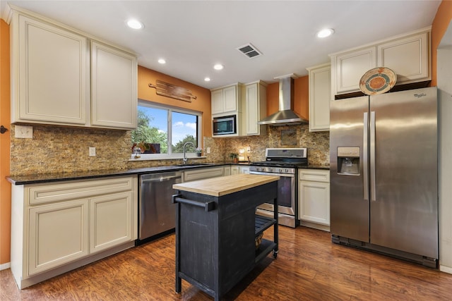 kitchen featuring dark wood-style flooring, a sink, butcher block counters, stainless steel appliances, and wall chimney exhaust hood