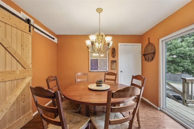 dining area with baseboards, a barn door, wood finished floors, and an inviting chandelier