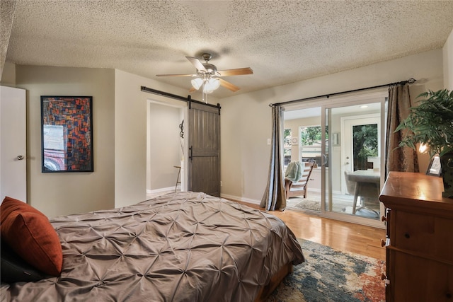 bedroom featuring a barn door, a textured ceiling, wood finished floors, and access to exterior