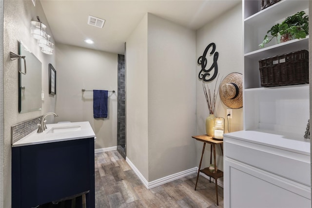 bathroom featuring visible vents, vanity, wood finished floors, baseboards, and recessed lighting