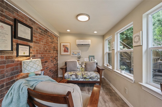 sitting room with a wall mounted air conditioner, brick wall, recessed lighting, baseboards, and wood finished floors