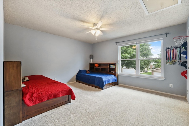 bedroom with a ceiling fan, attic access, a textured ceiling, baseboards, and carpet