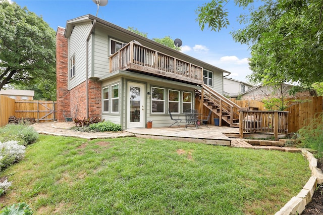 rear view of house with stairs, brick siding, a deck, a fenced backyard, and a yard