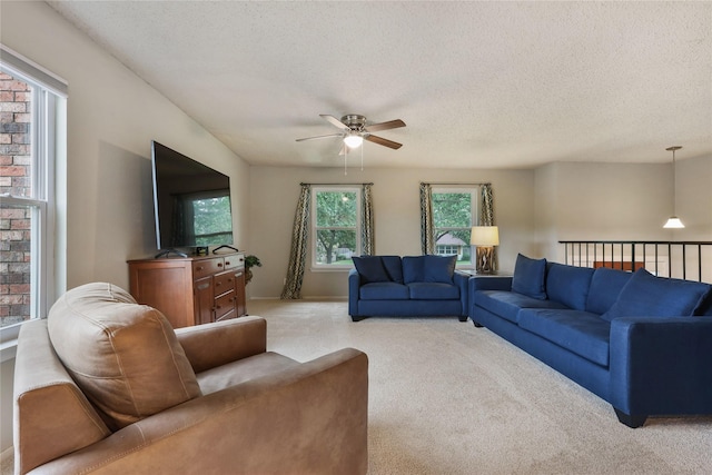 living area featuring light colored carpet, a ceiling fan, and a textured ceiling