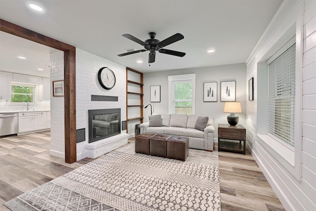 living room featuring recessed lighting, a large fireplace, and light wood-type flooring
