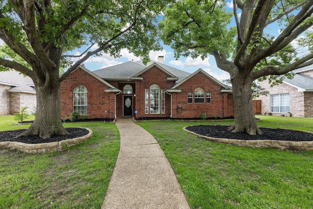 view of front of house with brick siding, a front lawn, roof with shingles, and a chimney