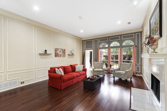 living room with wood finished floors, a decorative wall, a tile fireplace, and visible vents