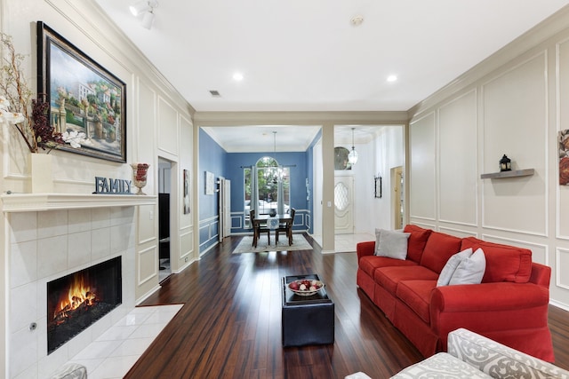 living area featuring visible vents, ornamental molding, a decorative wall, recessed lighting, and dark wood finished floors