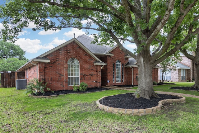 view of front of home featuring brick siding, fence, a front yard, and cooling unit