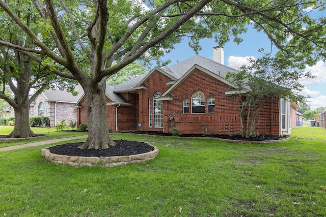 view of front of property featuring brick siding, a chimney, and a front lawn