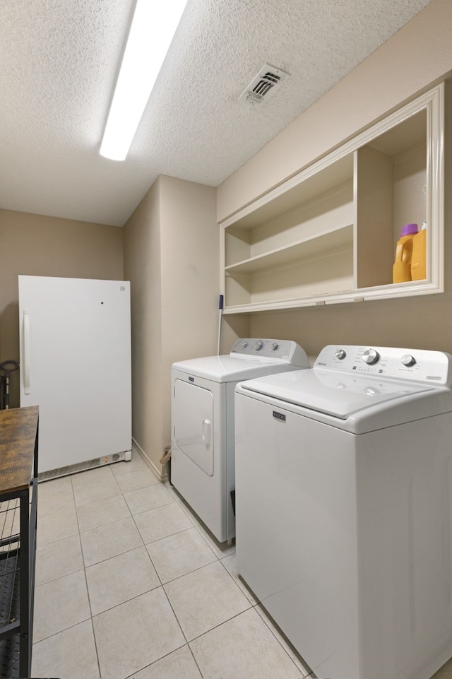 laundry room with laundry area, a textured ceiling, visible vents, light tile patterned floors, and separate washer and dryer