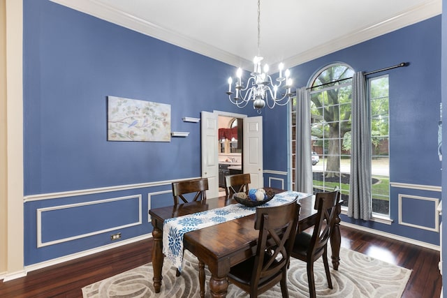 dining room with crown molding, a notable chandelier, wainscoting, baseboards, and wood finished floors