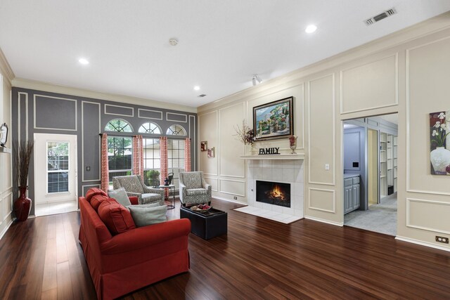 living area featuring crown molding, a fireplace, a decorative wall, recessed lighting, and visible vents