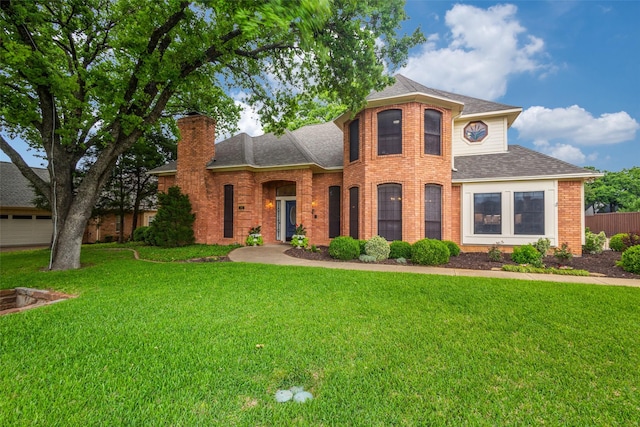 view of front of property with roof with shingles, fence, brick siding, a front yard, and a chimney