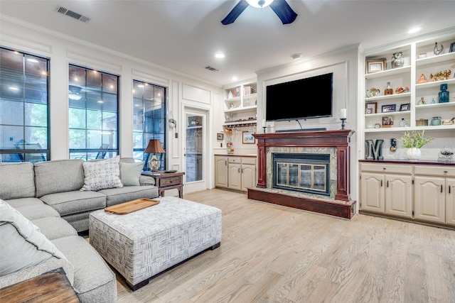 living area with crown molding, ceiling fan, light wood finished floors, and visible vents