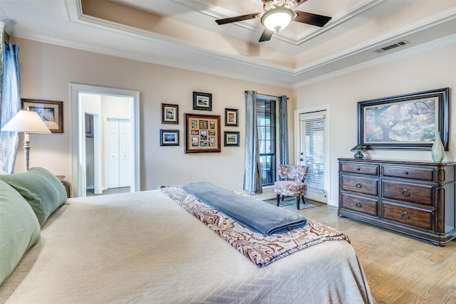 bedroom featuring crown molding, ceiling fan, a raised ceiling, light wood-style flooring, and visible vents