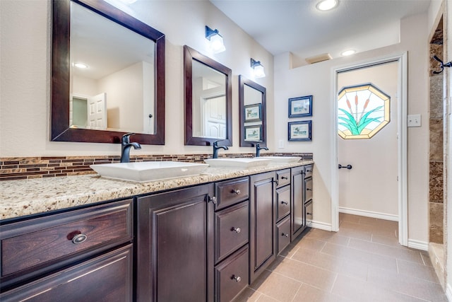 full bath with double vanity, decorative backsplash, tile patterned flooring, a sink, and baseboards