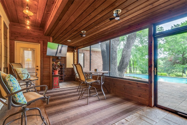 sunroom with wood ceiling, wood walls, and stone finish flooring