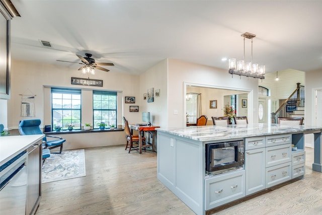kitchen featuring ceiling fan, light wood-style flooring, built in microwave, decorative light fixtures, and visible vents