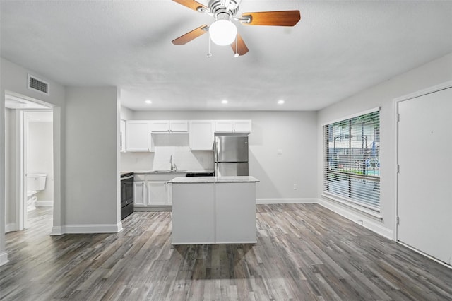 kitchen featuring visible vents, freestanding refrigerator, baseboards, a sink, and range with electric cooktop