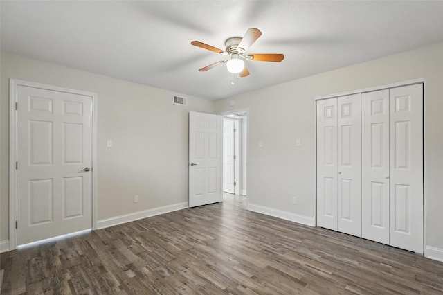 unfurnished bedroom with dark wood-style flooring, baseboards, visible vents, and a closet