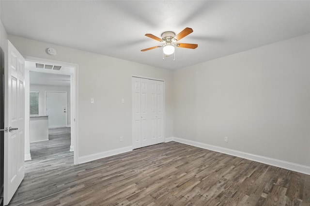 unfurnished bedroom featuring a ceiling fan, visible vents, wood finished floors, baseboards, and a closet