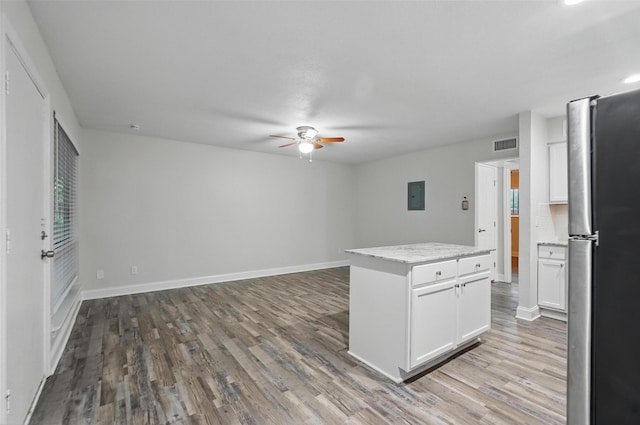kitchen featuring freestanding refrigerator, ceiling fan, wood finished floors, and electric panel
