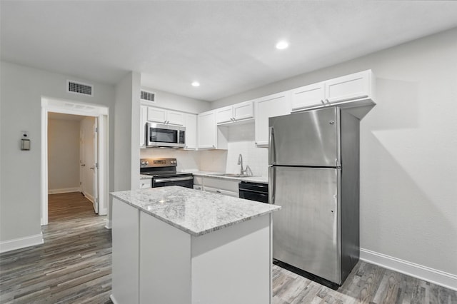 kitchen with appliances with stainless steel finishes, a sink, white cabinetry, baseboards, and visible vents