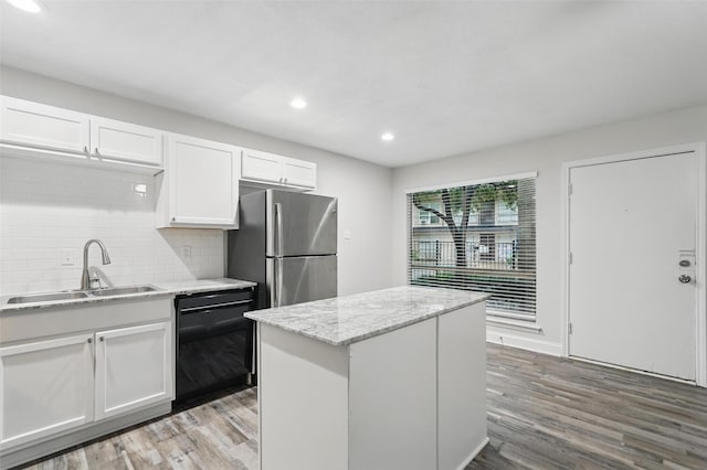 kitchen featuring white cabinets, a sink, dishwasher, freestanding refrigerator, and backsplash
