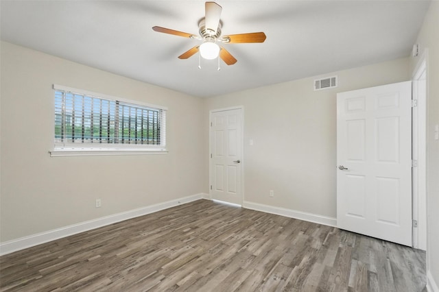 unfurnished bedroom with a ceiling fan, baseboards, visible vents, and wood finished floors