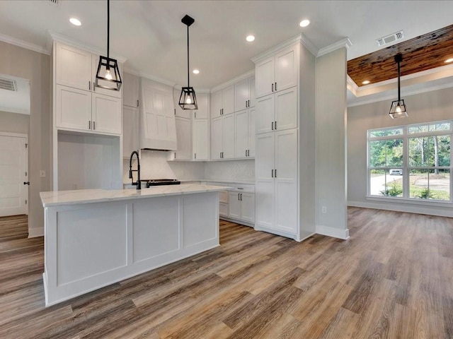 kitchen featuring white cabinets, baseboards, wood finished floors, visible vents, and ornamental molding