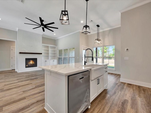 kitchen with a sink, light wood-style floors, dishwasher, a large fireplace, and white cabinetry