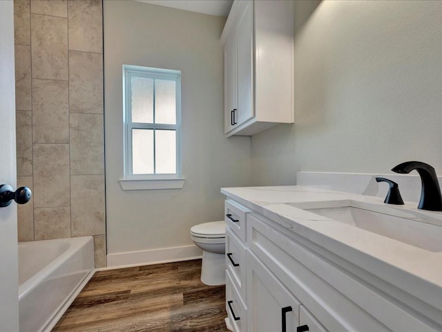 full bathroom with toilet, baseboards, wood finished floors, and vanity